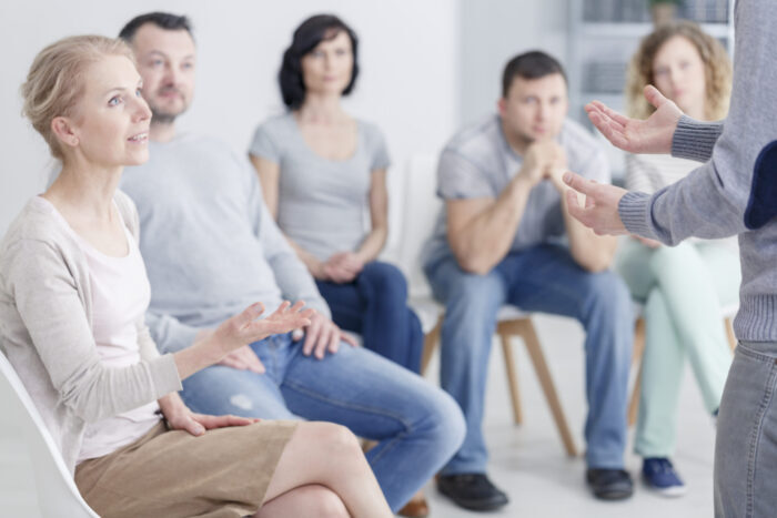 Woman,Psychologist,Speaking,During,Group,Psychotherapy,Session Illustrasjon fra Shutterstock. Viser mennesker i gruppe